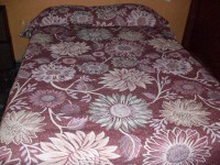 Colcha doble vista color guinda, diseño en flores.